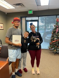 a family holding a christmas card in front of a christmas tree